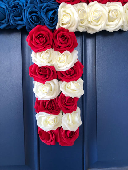 Red, White and Blue Roses in the shape of a cross on a blue door