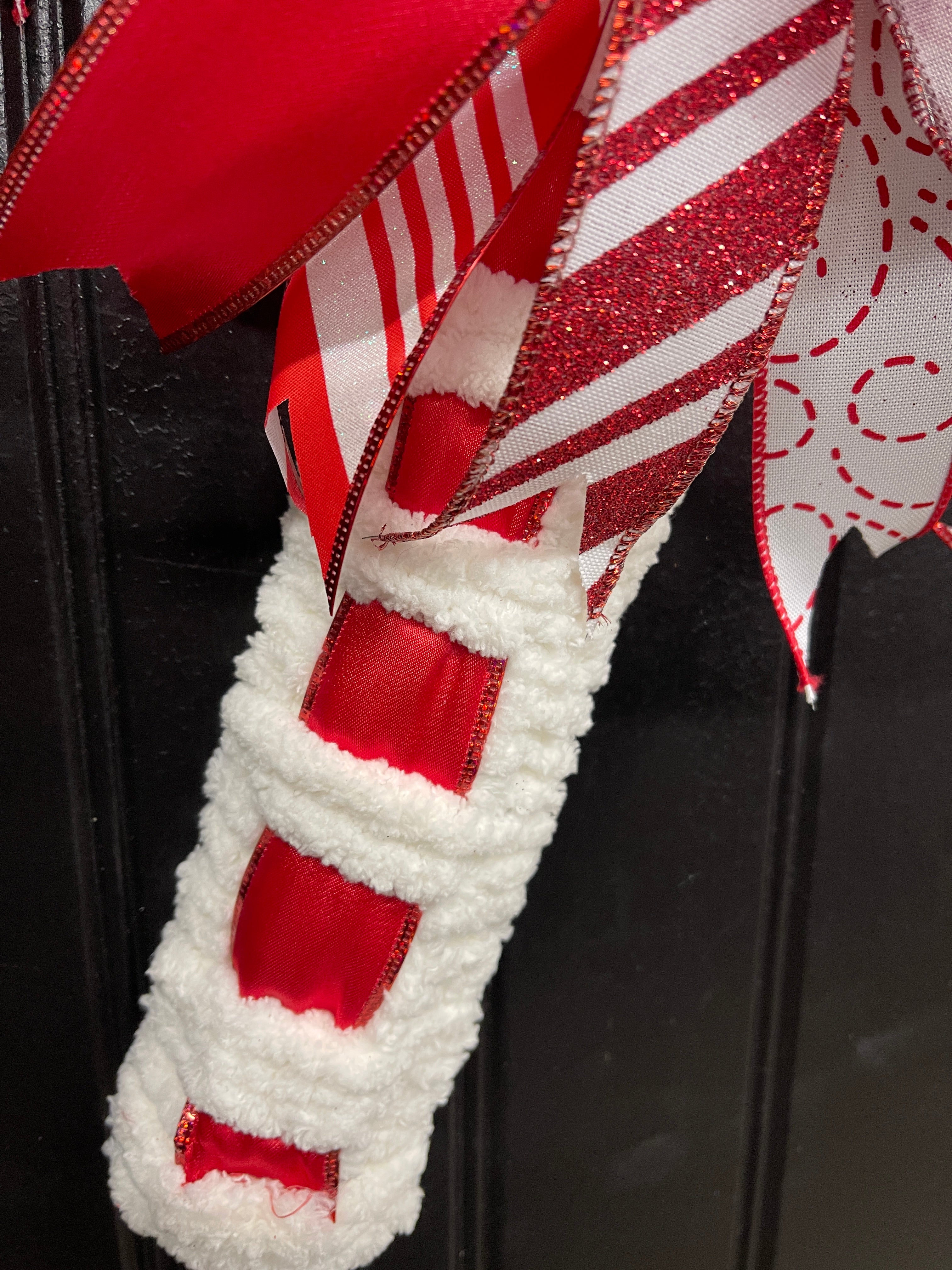 Close up of  Red and White Candy Cane Chenille Yarn and Ribbon Christmas Wreath with Red and White Striped Bow for Front Door. 