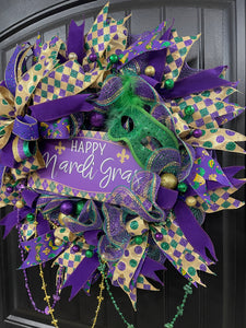 Right Side View of Purple, Green and Gold Mardi Gras Wreath with Beads, Balls, Mask and Bow on a Black Door