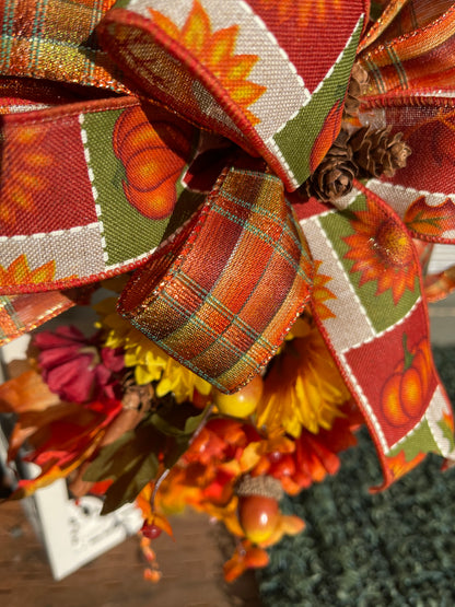 Close Up Detail of Ribbon in Fall Bow with Orange, Red, tan, Green and White, with Pumpkins and Sunflowers on the Print, Pine Cones in the Center of the Bow