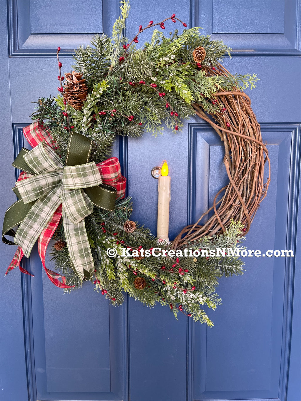 Christmas Grapevine Wreath with Artificial Pine Branches, Red Berries, Pinecones, with a Red, White and Green Bow and an Artificial Battery Operated Candle in the Center on a Blue Door