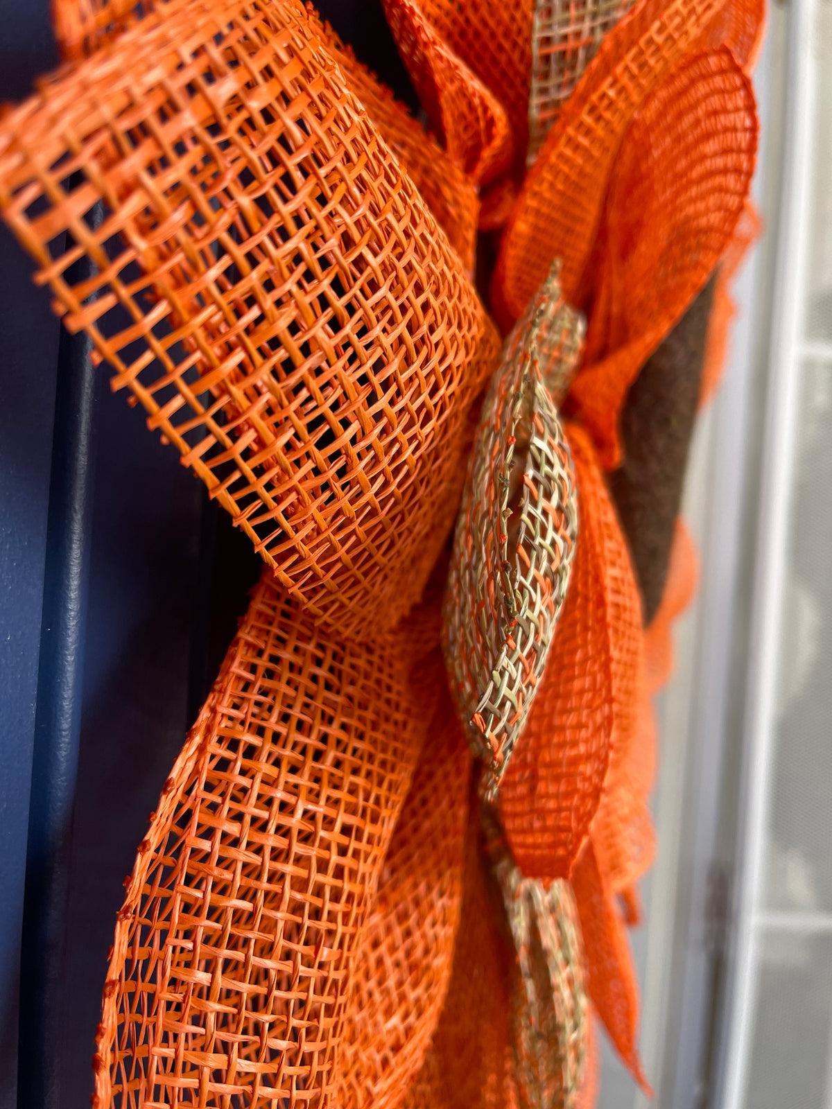 Side View of Poly Burlap Mesh Sunflower Wreath Featuring Orange and Patterned Colors of Yellow, Brown and Orange with a Brown Center on a Blue Door