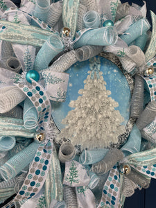 Close Up Detail of Blue Round Metal Sign with a White Flocked Christmas Tree with a Blue Bow