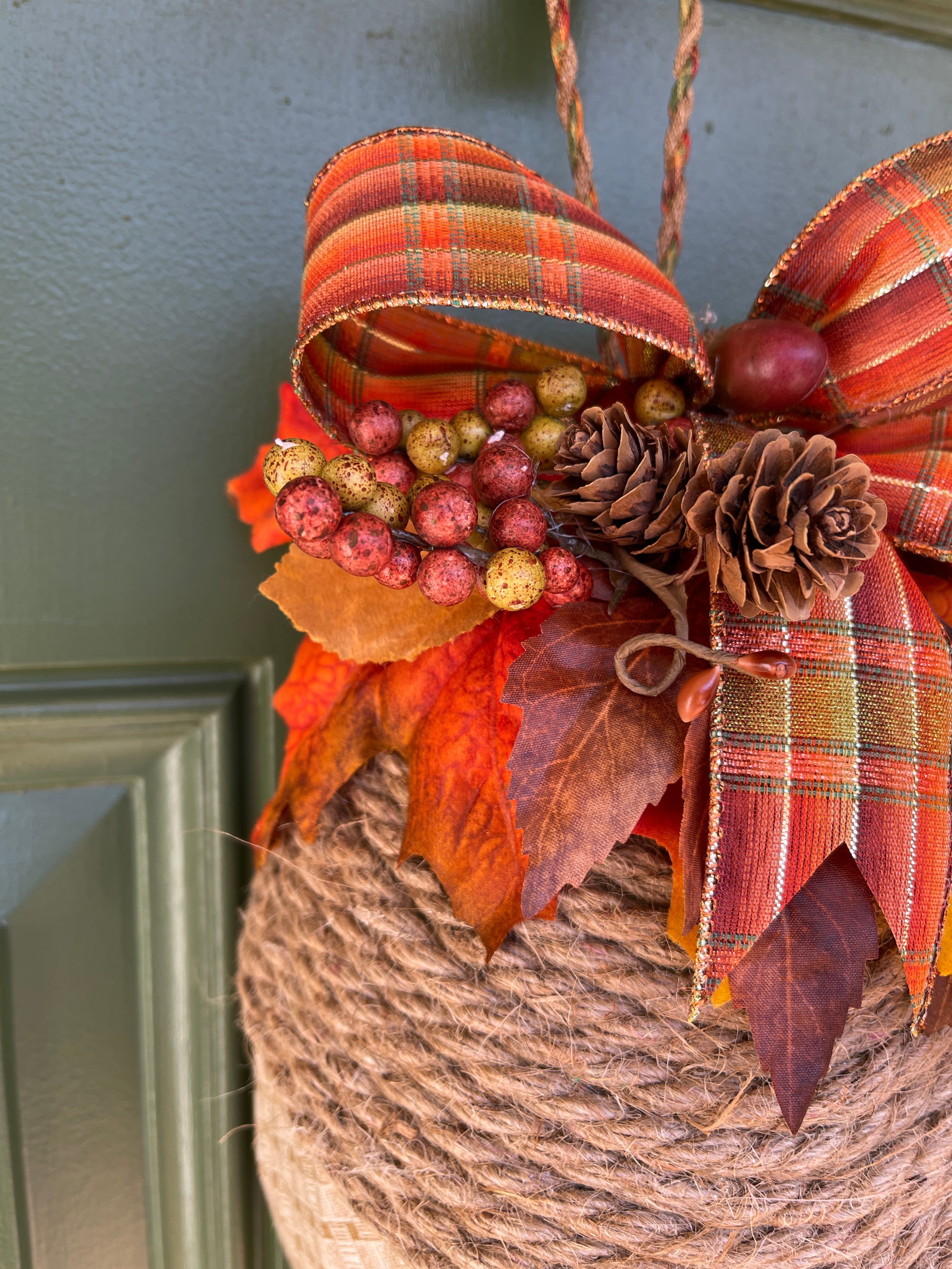 Close up of Bow with Pinecones, Berries and Leaves on an Acorn Shaped Wreath 