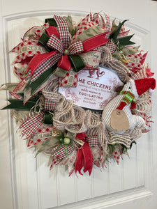 Left Side View of Red, White and Green Deco Mesh Christmas Chicken Wreath with Stuffed Chicken Wearing a Santa hat with Sign, The Chickens were nesting all snug in their beds while visions of egg laying danced in their heads.