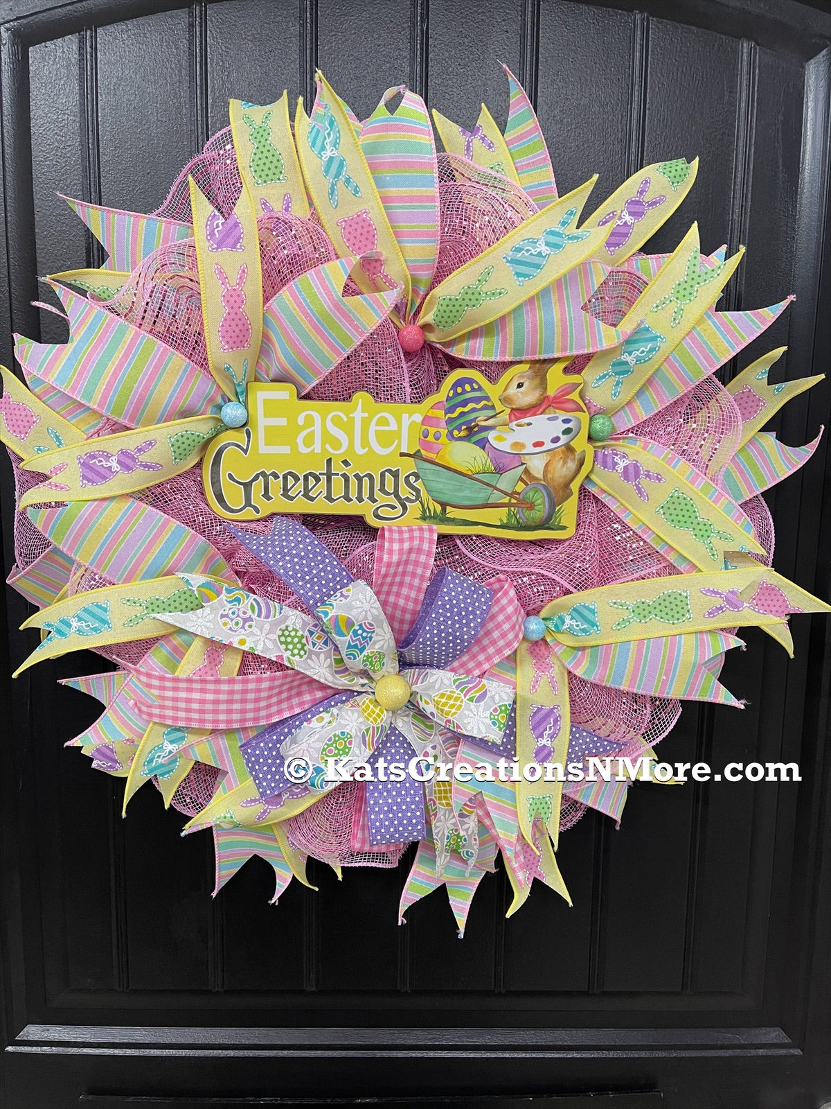 Easter Greetings Bunny Wreath with Pink, Yellow, Blue, Green and Purple Pastel Ribbons and Bows on a Black Door